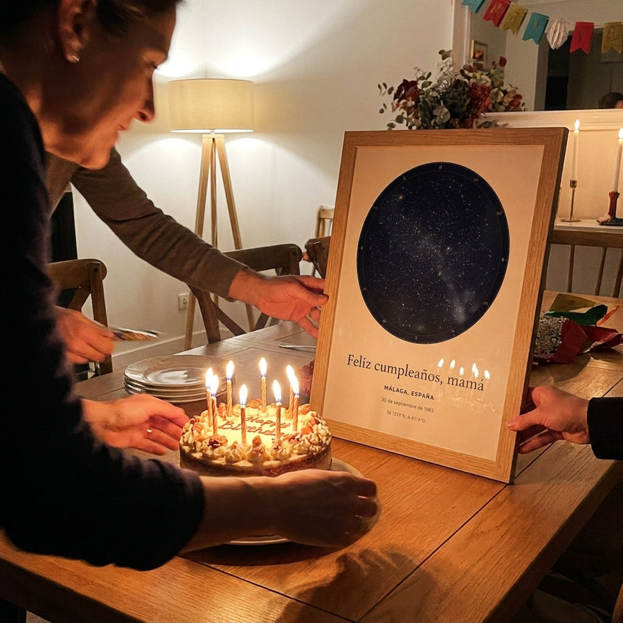 Quadro mapa estelar personalizado de aniversário ao lado de um bolo com velas acesas