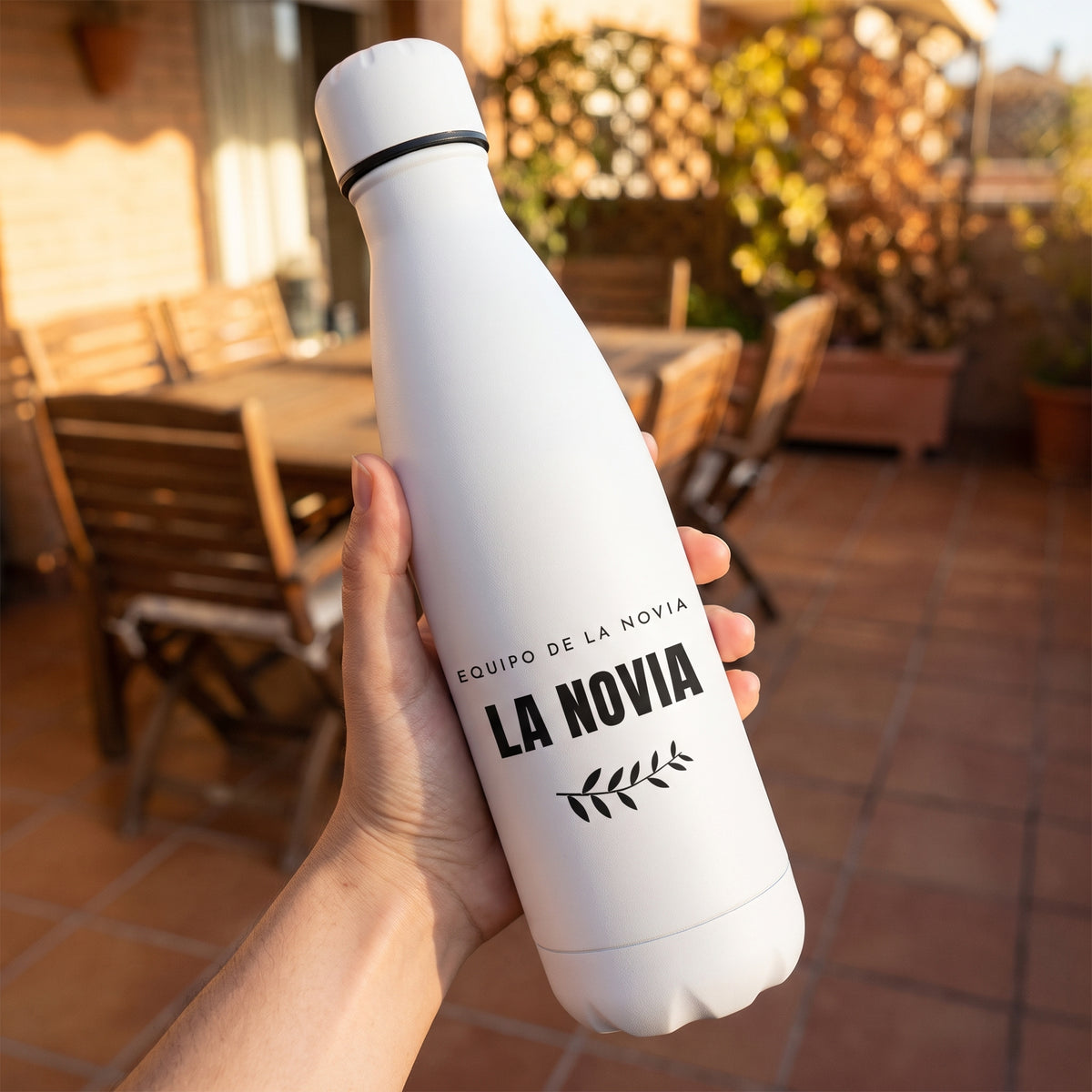 Una mano sostiene la botella de LA NOVIA con su rama de olivo