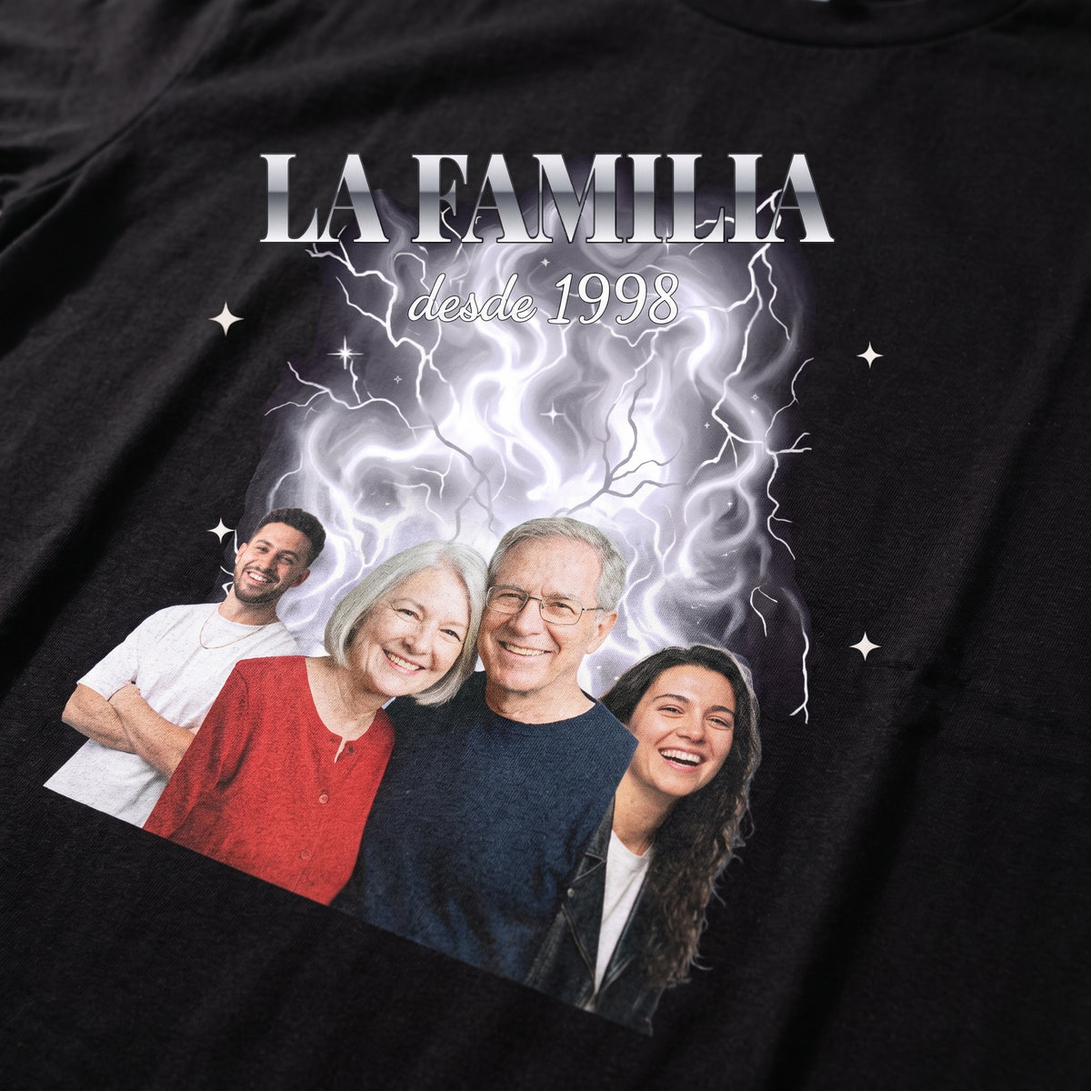 Detalle del estampado DTF estilo bootleg con cuatro personas recortadas sobre humo plateado y rayos, «LA FAMILIA» en letras cromadas y «desde 1998», sobre una camiseta negra