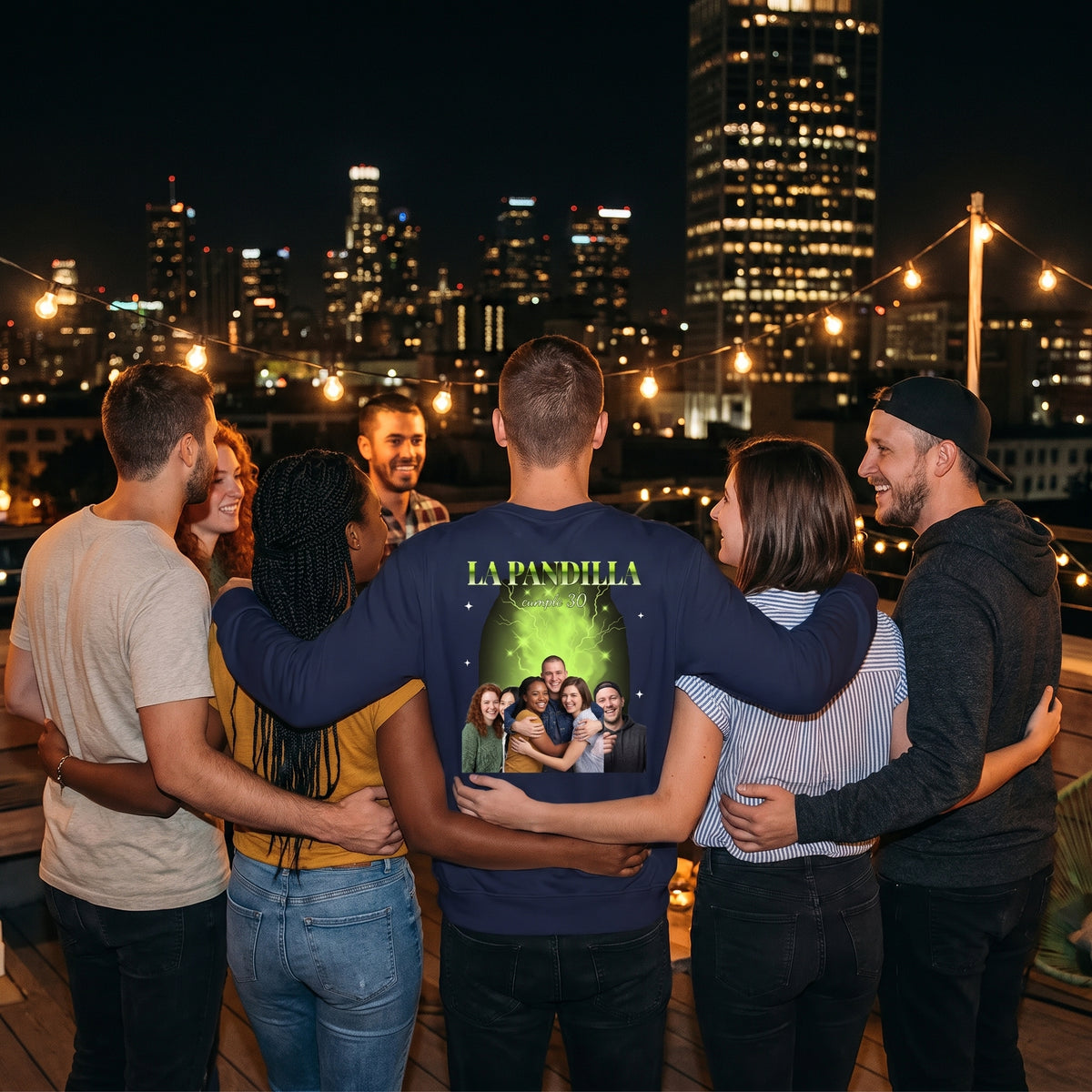 Grupo de amigos en una fiesta en una azotea; el del centro lleva la sudadera azul marino personalizada estilo bootleg con sus fotos sobre humo verde ácido y «LA PANDILLA» en la espalda