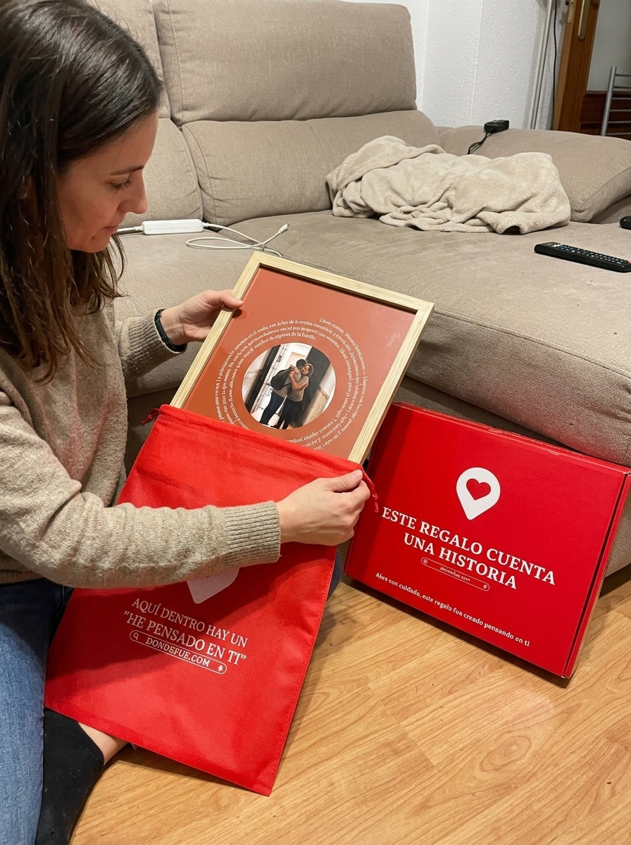 Sacando el cuadro canción personalizado de casa nueva de la bolsa de regalo, con la caja abierta al lado