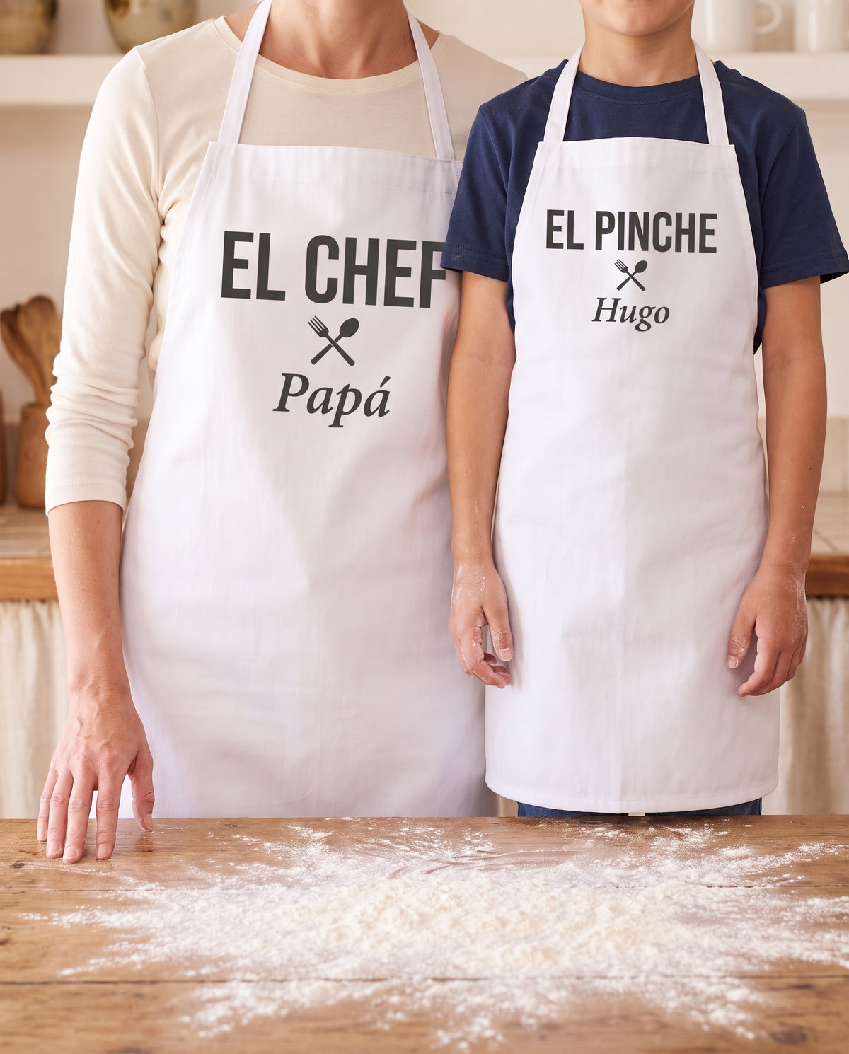 Un adulto y un niño cocinando juntos con los dos delantales a juego puestos: «EL CHEF · Papá» y «EL PINCHE · Hugo»