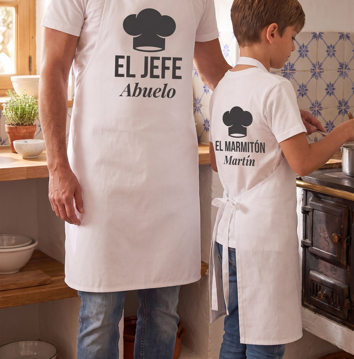 Un abuelo y su nieto en los fogones con los delantales de la composición del gorro de chef: «EL JEFE · Abuelo» y «EL MARMITÓN · Martín»