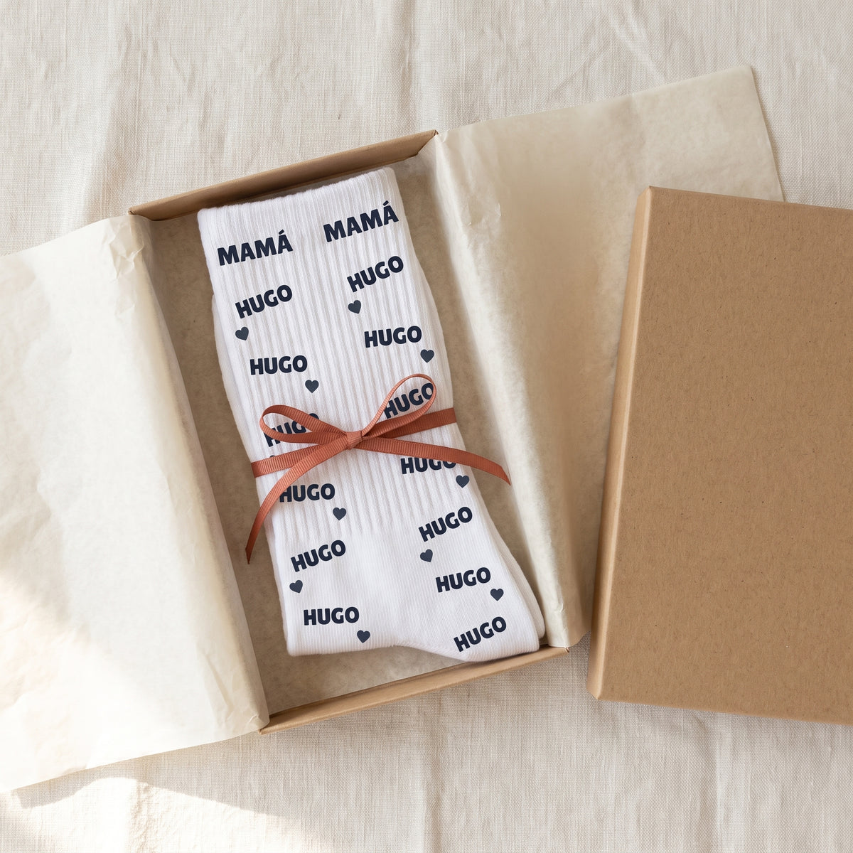Los calcetines personalizados doblados en una caja de regalo con lazo, listos para regalar