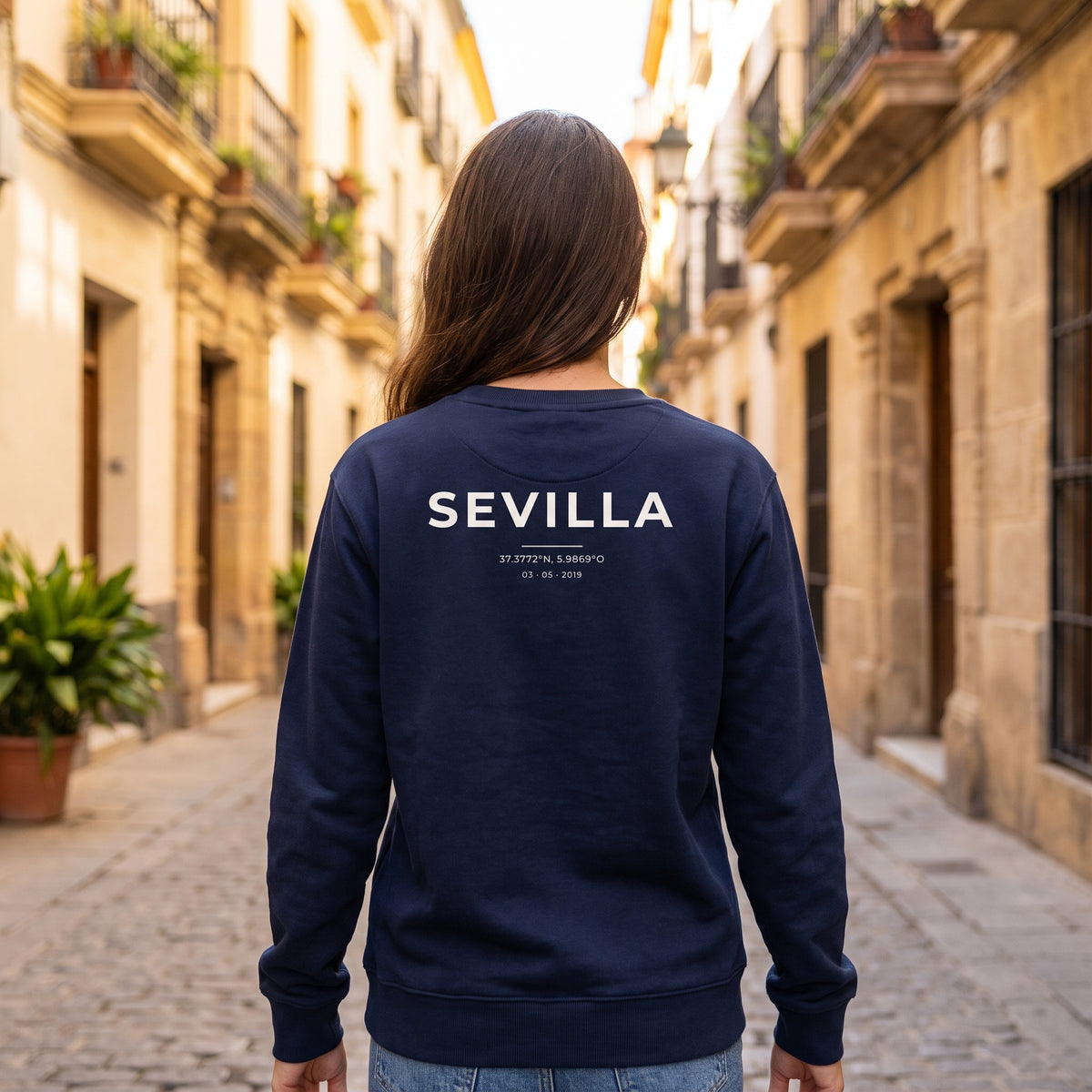 Mujer de espaldas con la sudadera azul marino personalizada con Sevilla y sus coordenadas estampado en la espalda