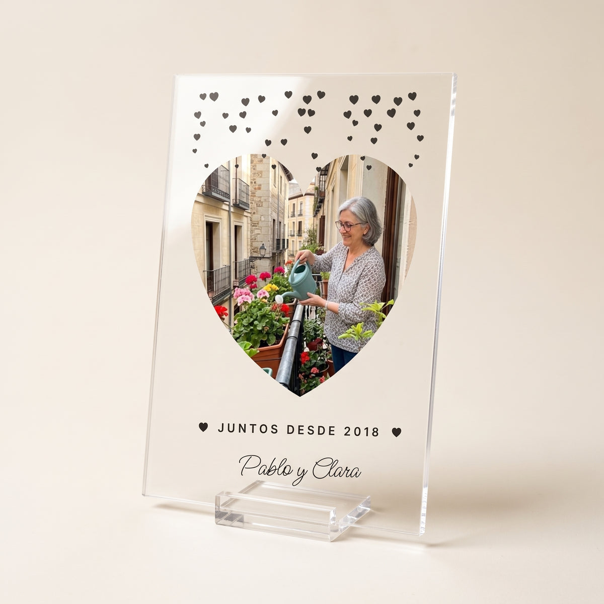 Placa de metacrilato personalizada con corazoncitos en su peana transparente, foto de estudio sobre fondo cálido neutro
