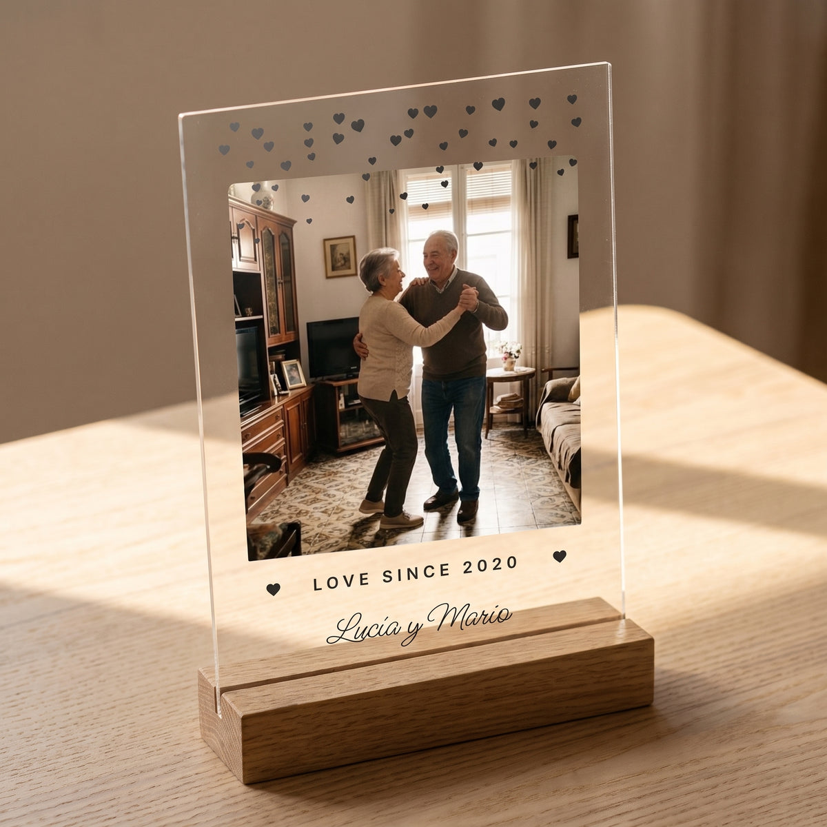 Placa de metacrilato personalizada con corazoncitos encajada en su base de roble, con la luz apagada