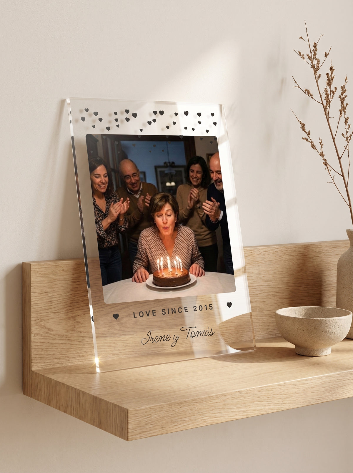 Placa de metacrilato personalizada con corazoncitos apoyada en una balda de roble junto a un cuenco de cerámica y una rama seca