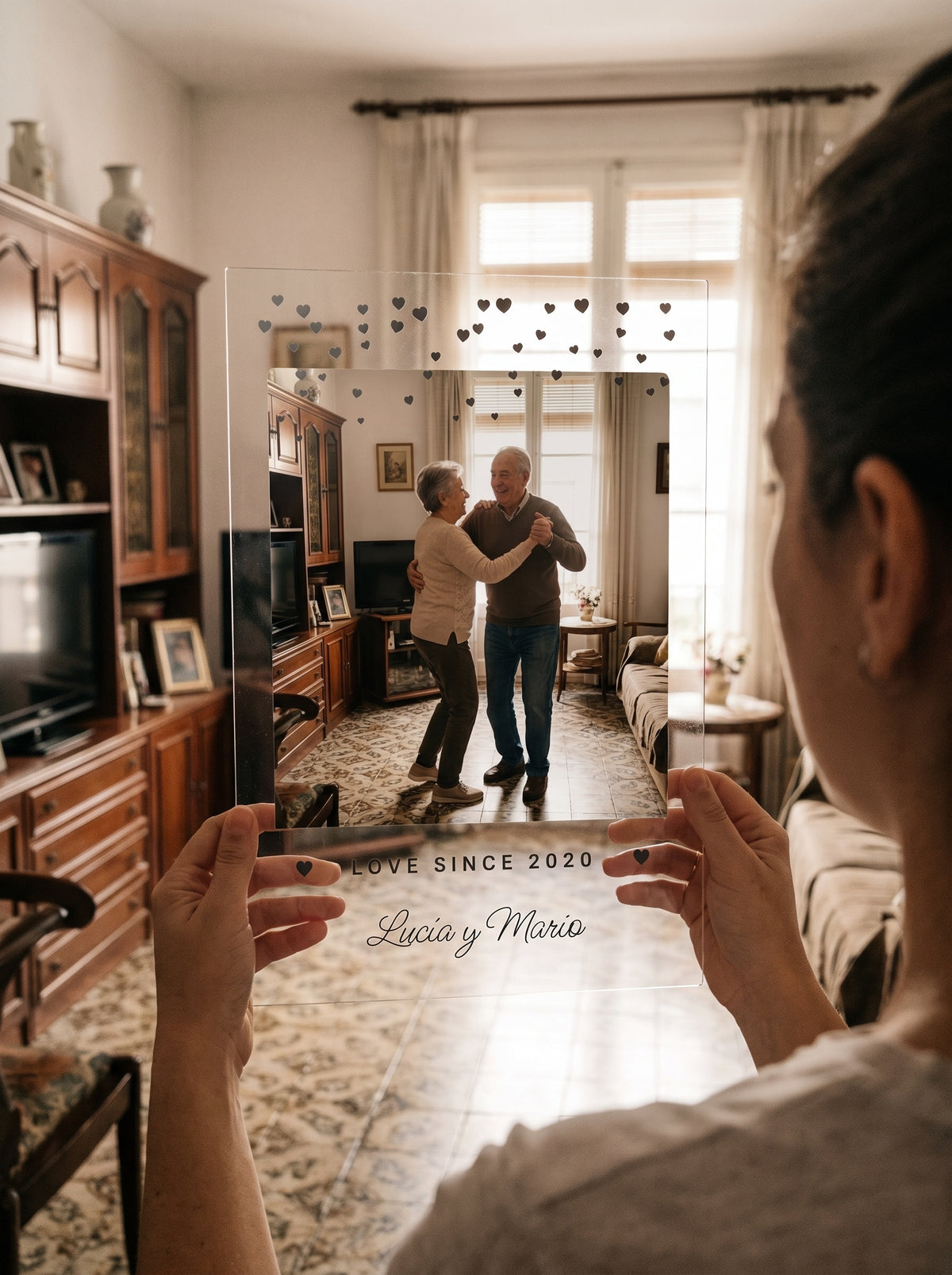 Sosteniendo la placa de metacrilato personalizada con corazoncitos a contraluz junto a una ventana