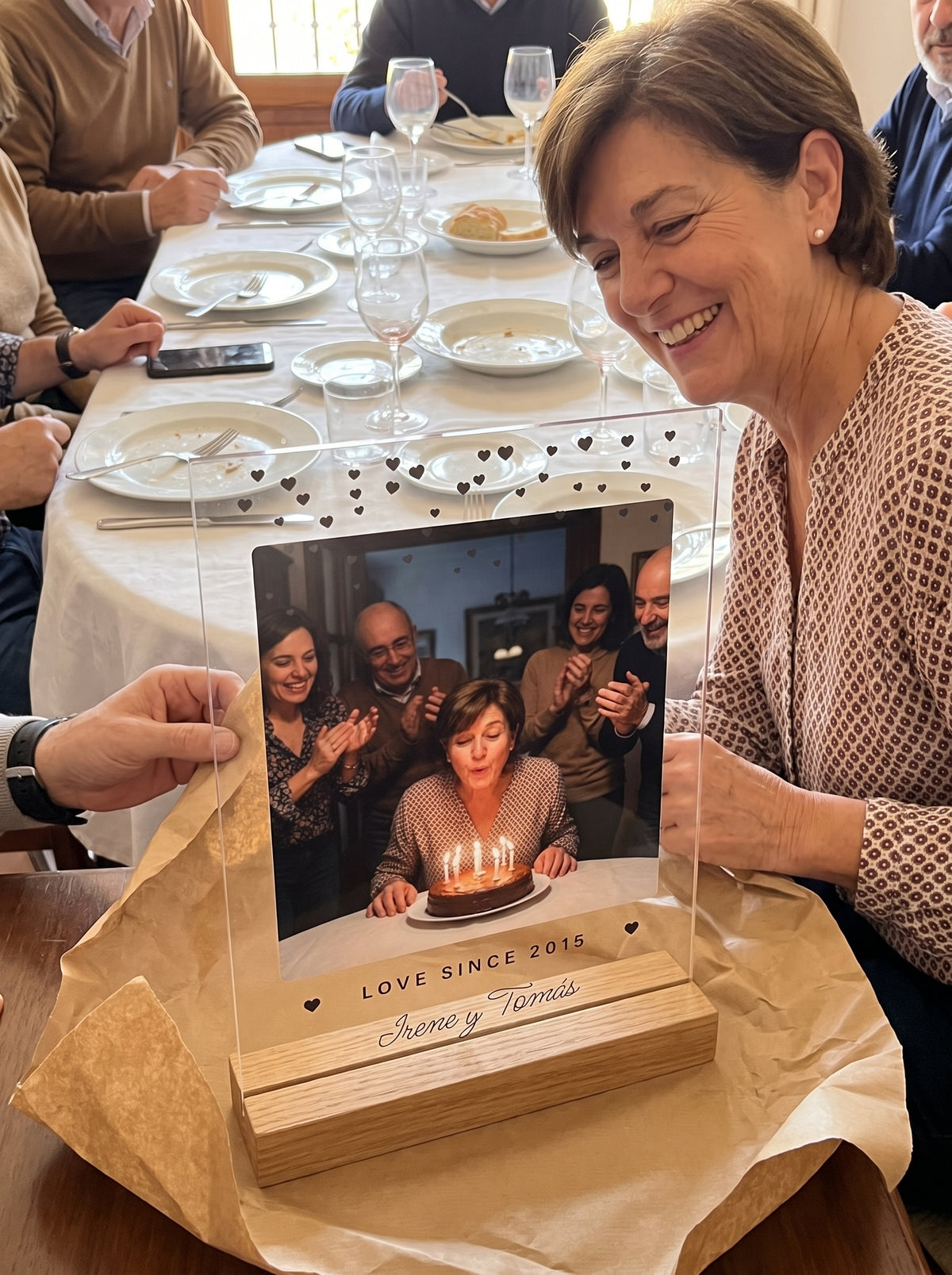 Abriendo el regalo de la placa de metacrilato personalizada con corazoncitos en una comida familiar