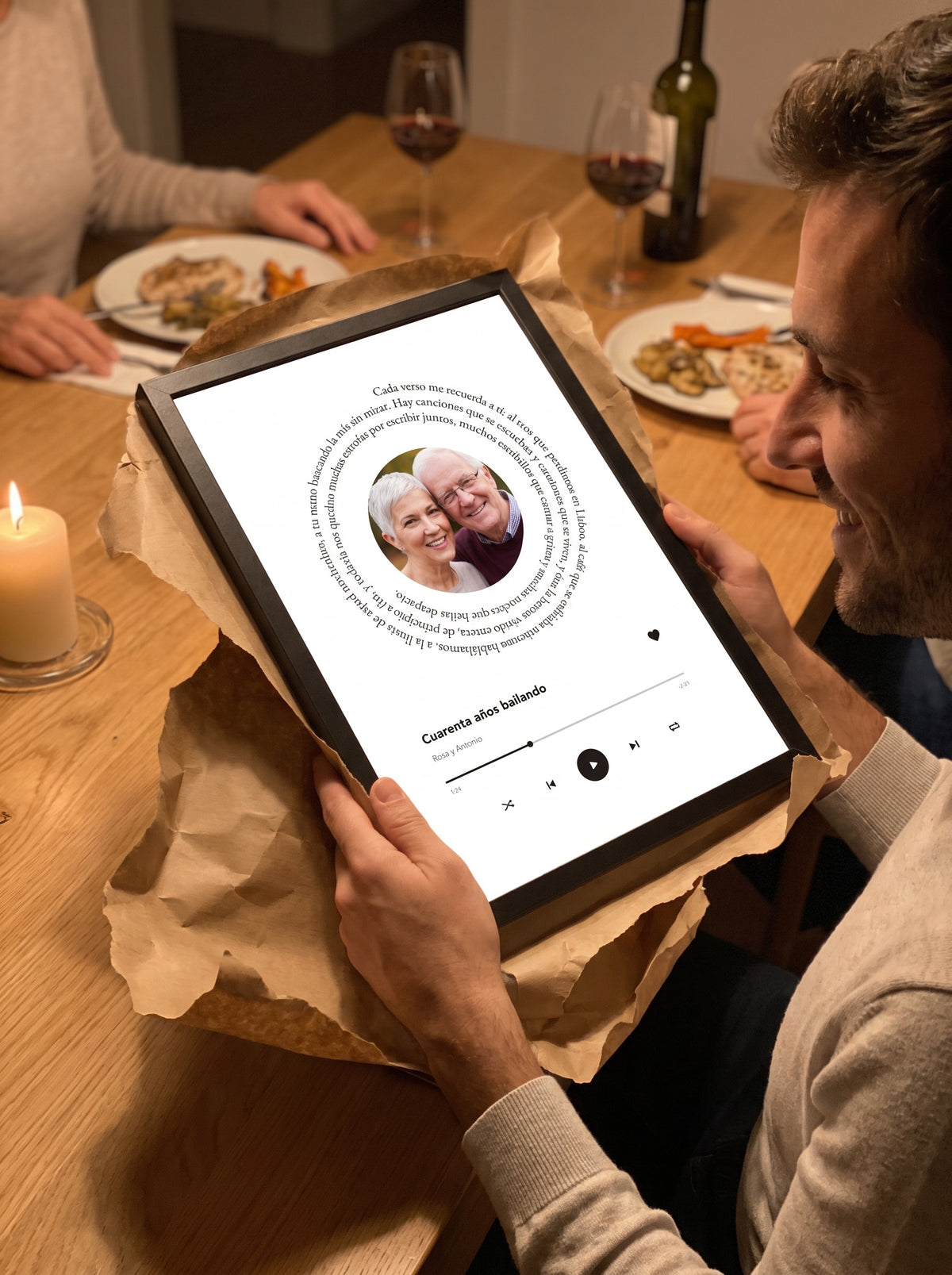 Un hombre desenvuelve en una cena de aniversario el cuadro de la canção con la foto de una pareja mayor