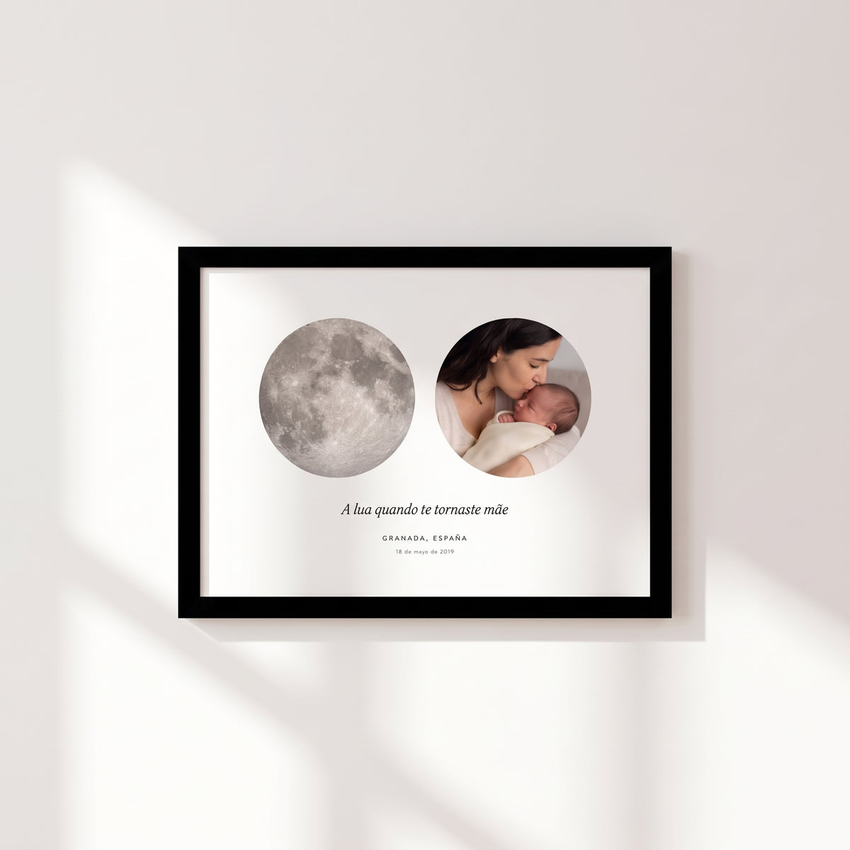 Cuadro apaisado con la luna de Granada del 18 de mayo de 2019 junto a la foto de una madre besando a su bebé, con marco negro