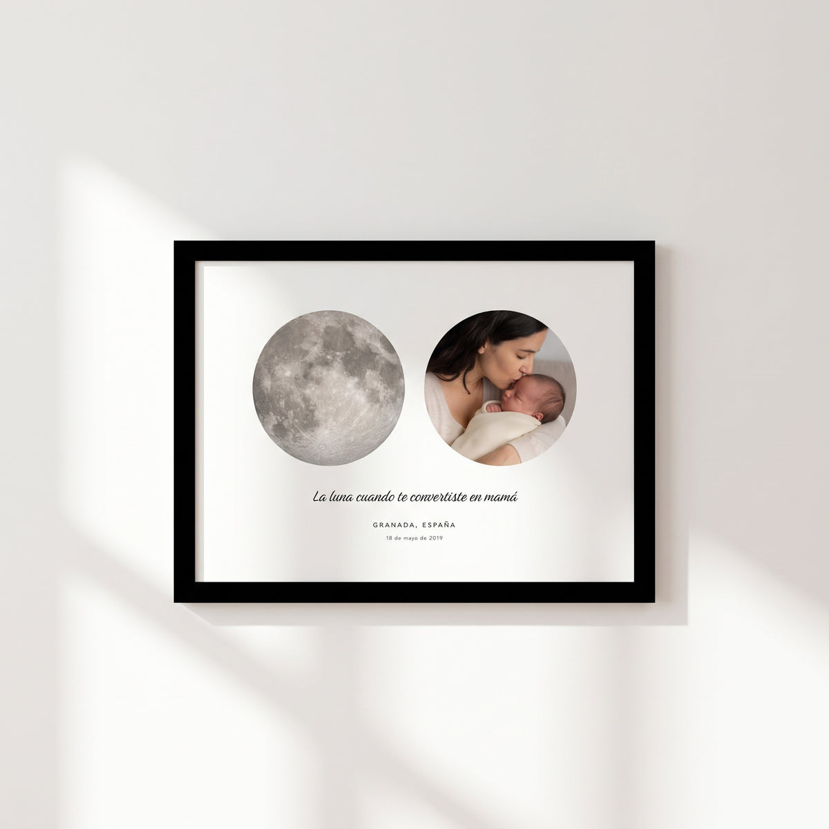 Cuadro apaisado con la luna de Granada del 18 de mayo de 2019 junto a la foto de una madre besando a su bebé, con marco negro