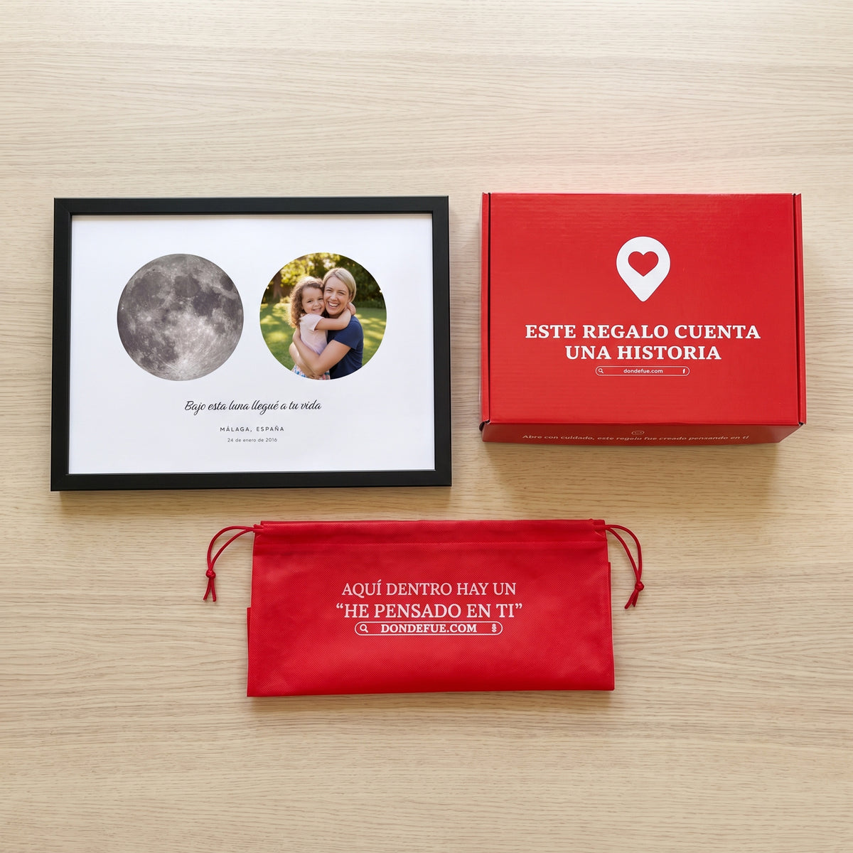 Cuadro La luna del día que fuiste mamá personalizado (Bajo esta luna llegué a tu vida · MÁLAGA, ESPAÑA) junto a la caja roja y la bolsa de tela roja en que se envía