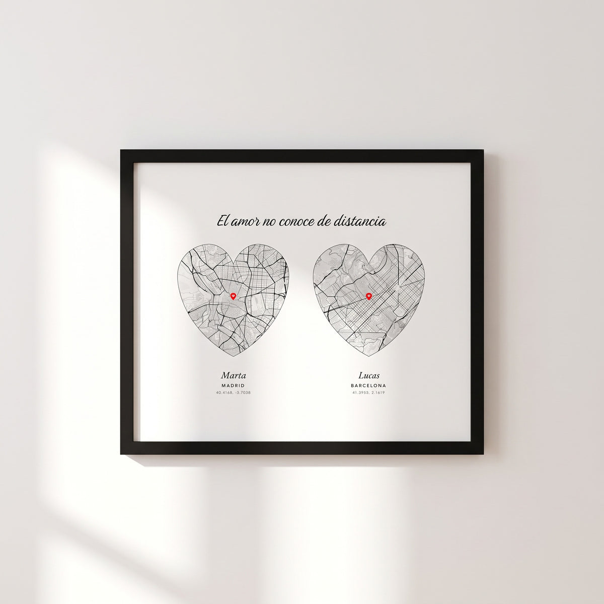 Cuadro de pareja a distancia apaisado con dos mapas en forma de corazón, Madrid y Barcelona, cada uno con su marcador, los dos nombres y las coordenadas, con marco negro