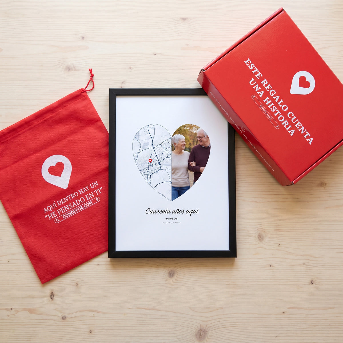Cuadro lugar y foto en corazón personalizado (Cuarenta años aquí · BURGOS) junto a la caja roja y la bolsa de tela roja en que se envía