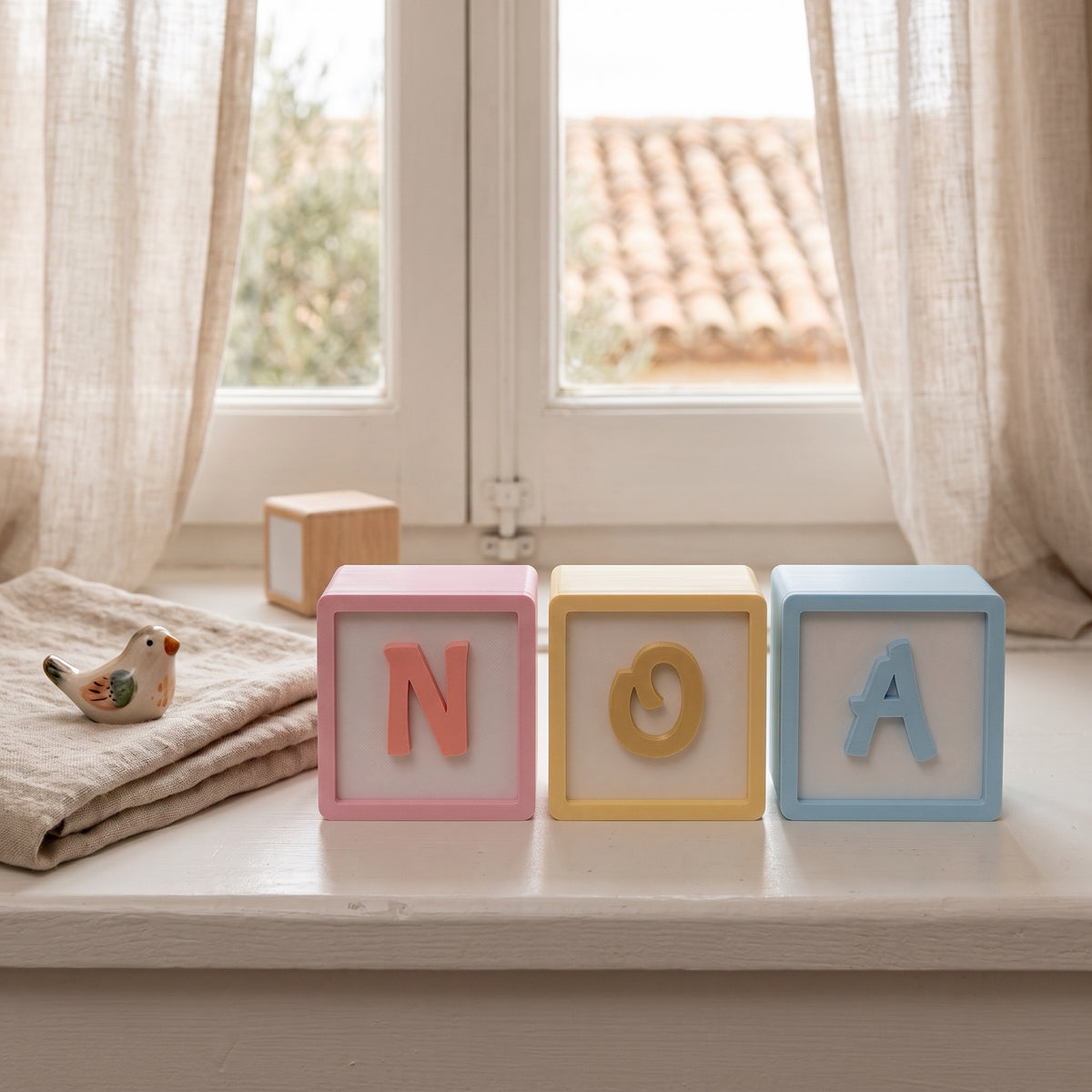 Cubos de letras 3D en tonos pastel junto a la ventana