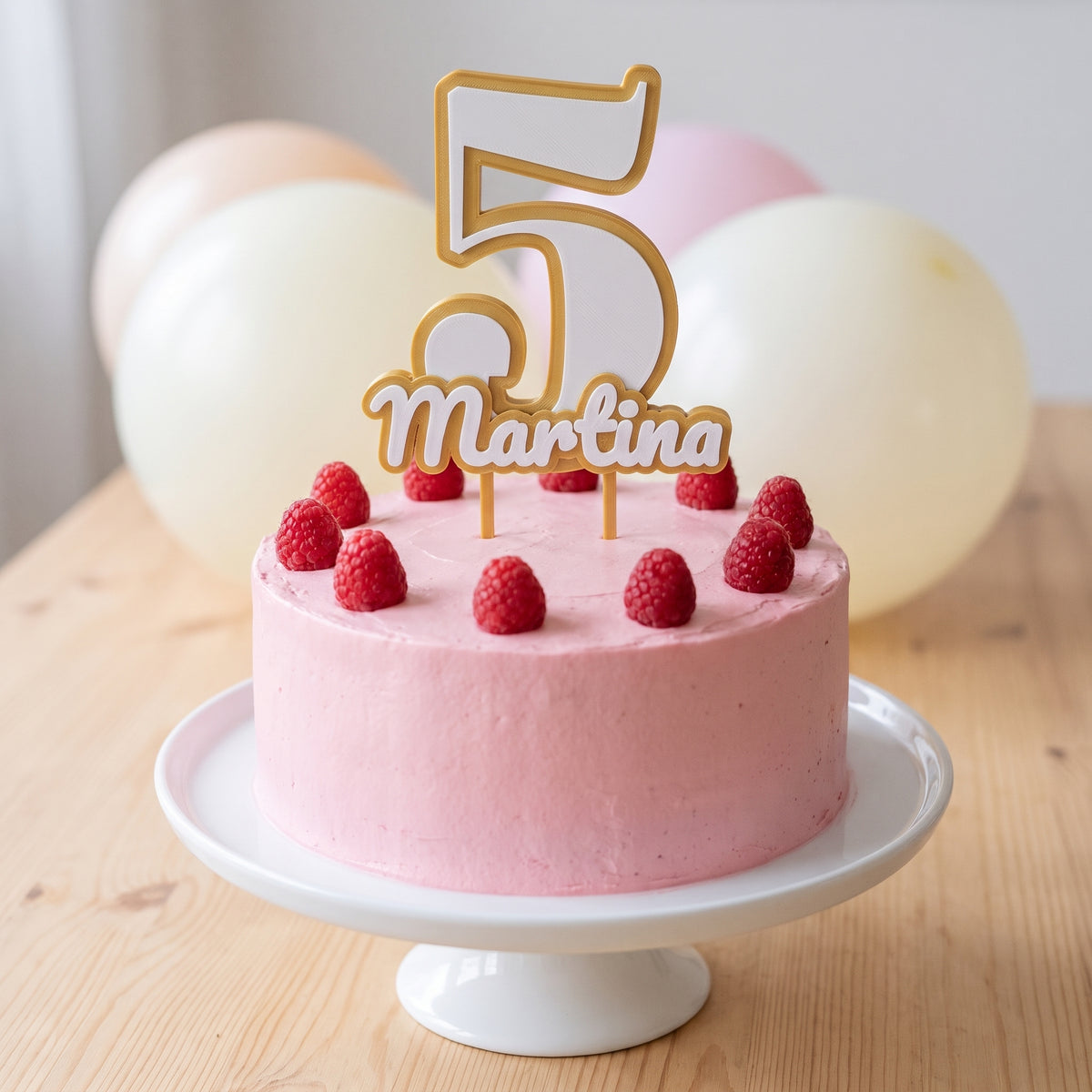 Cake topper personalizado impreso en 3D con el número 5 y el nombre Martina sobre una tarta rosa con frambuesas