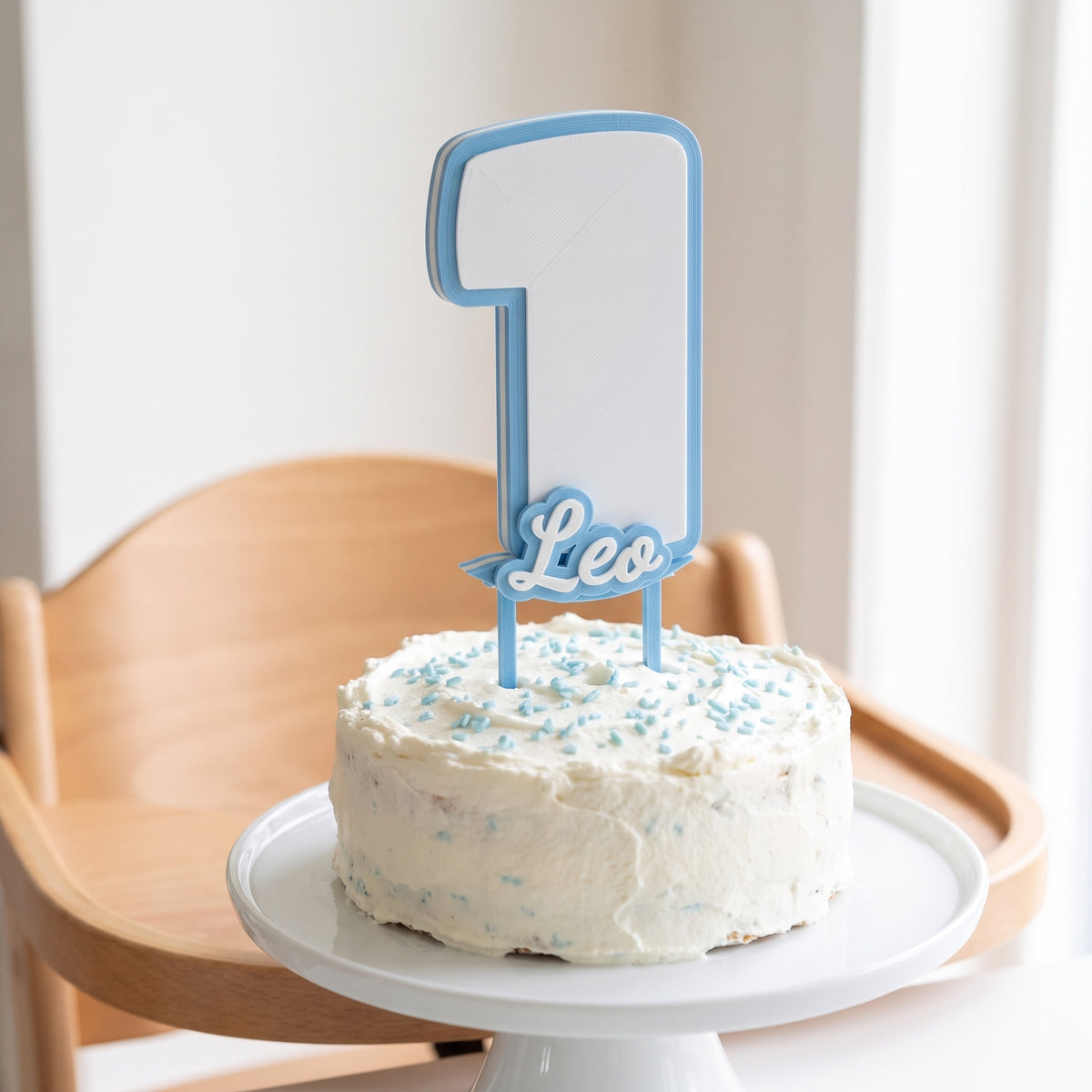 Cake topper personalizado de primer aniversário, número 1 y nombre Leo en azul, sobre una tarta pequeña