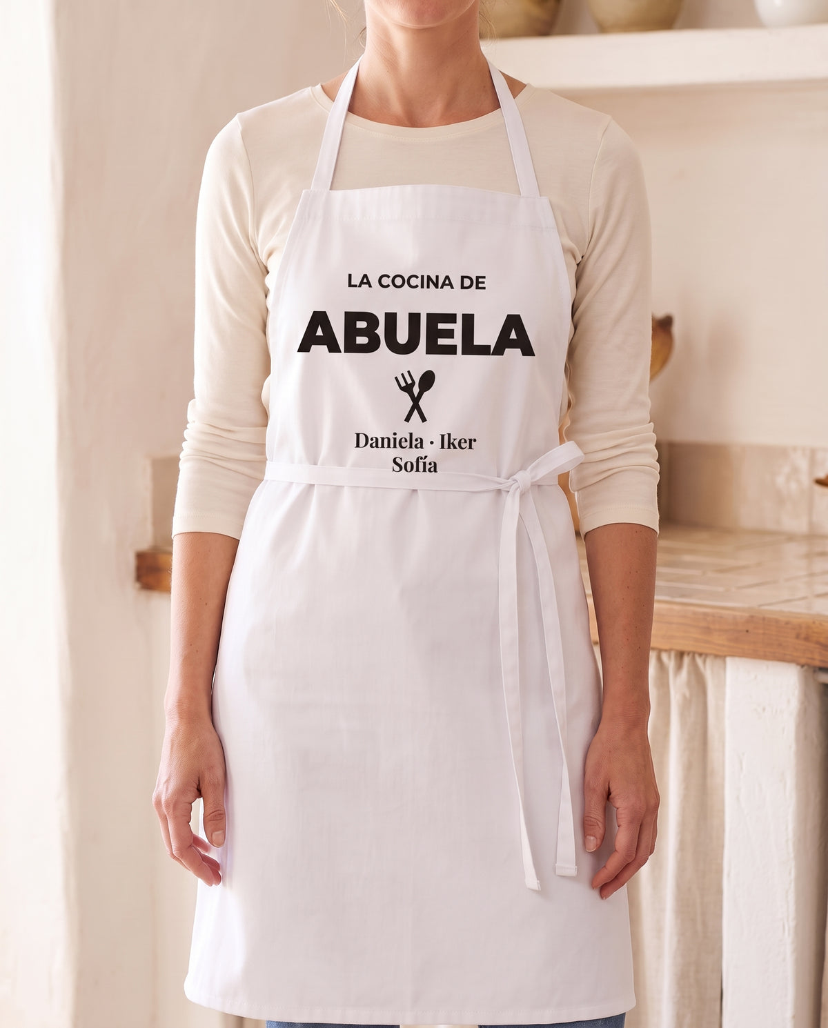 Mujer con un delantal personalizado que pone «LA COCINA DE ABUELA» y los nombres Daniela, Iker y Sofía