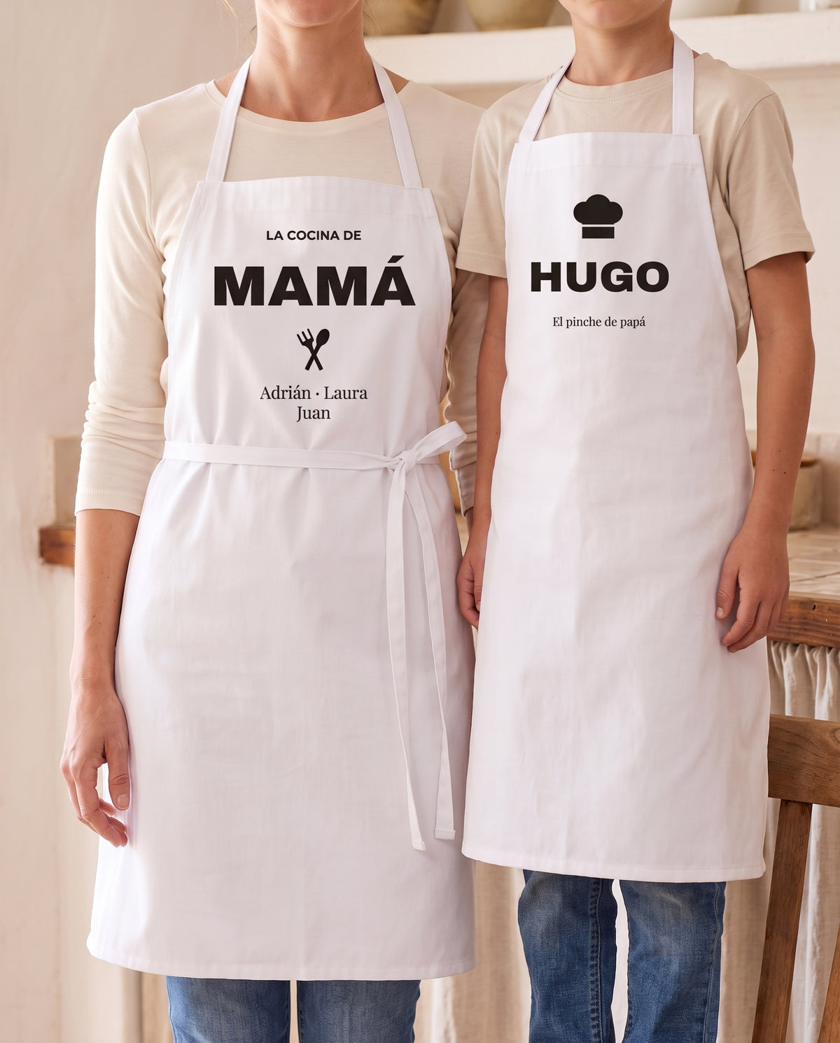 Delantal de adulto con «LA COCINA DE MAMÁ» y delantal de niño con gorro de chef y el nombre HUGO, puestos los dos en la cocina