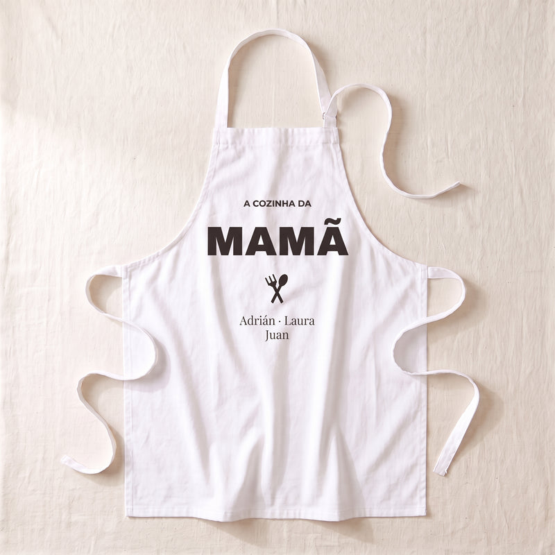 Delantal personalizado blanco extendido, con «LA COCINA DE MAMÁ», un tenedor y una cuchara cruzados y los nombres Adrián, Laura y Juan