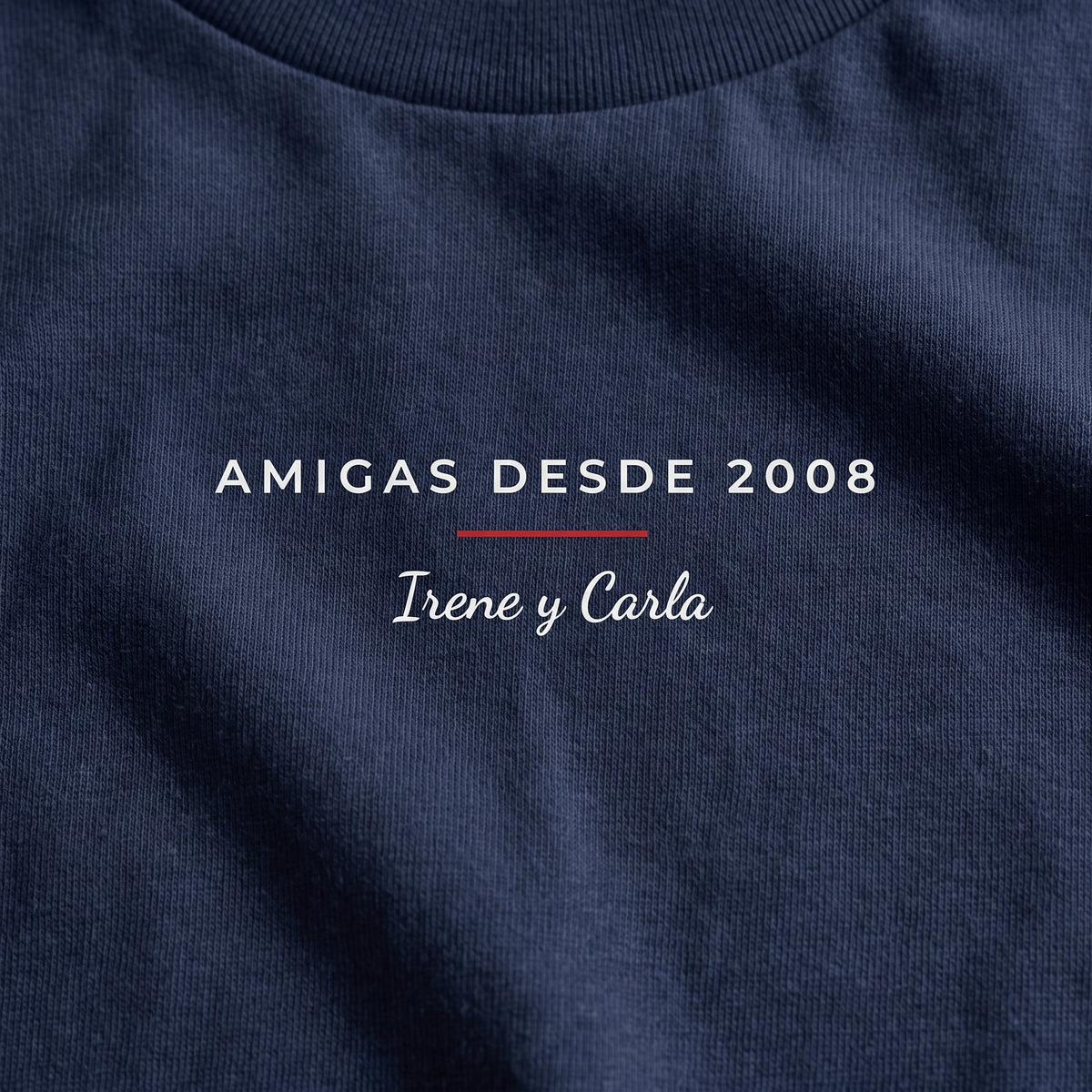 Detalle del estampado DTF sobre una camiseta azul marino: «AMIGAS DESDE 2008» con una línea roja e «Irene y Carla» a mano, estilo minimal