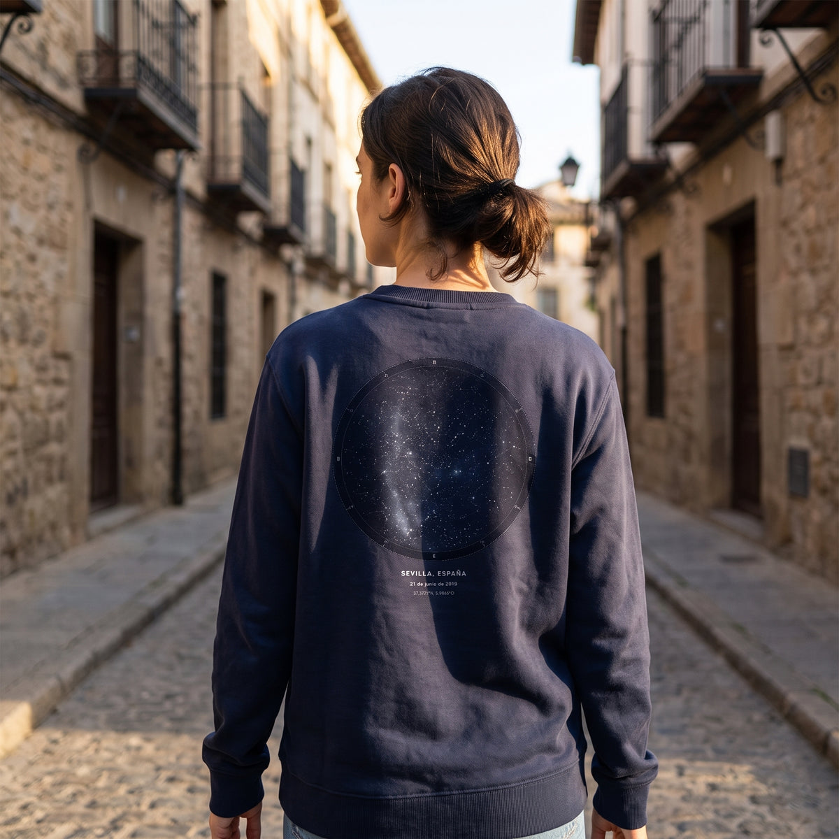 Mujer de espaldas con la sudadera azul marino personalizada con el mapa estelar del cielo de Sevilla estampado en la espalda