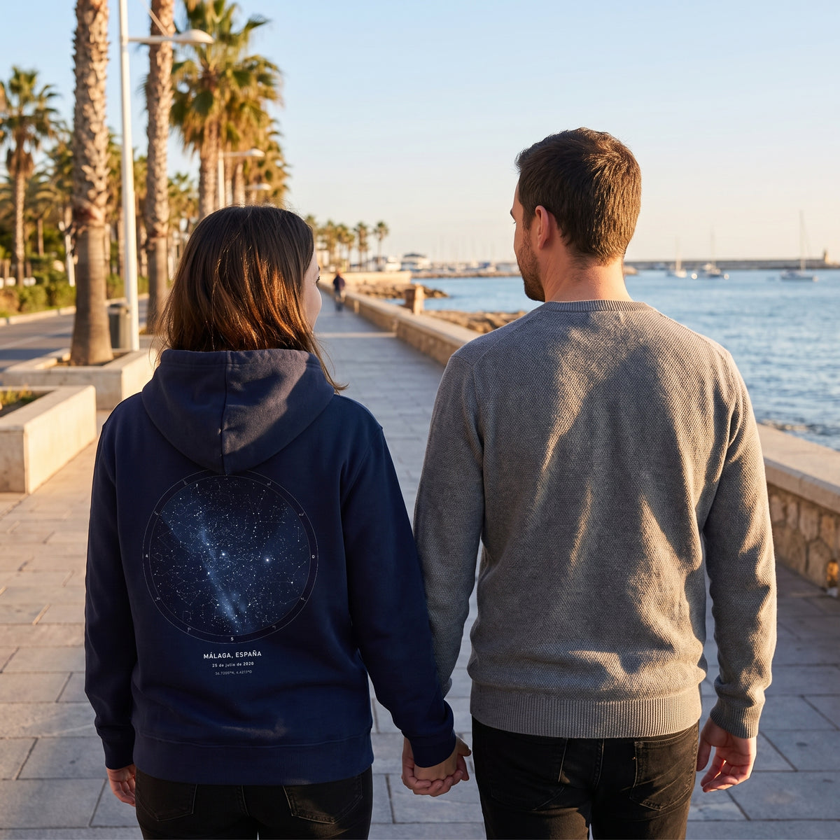 Paseo al atardecer con la sudadera con capucha azul marino personalizada con el mapa estelar del cielo de Málaga estampado en la espalda