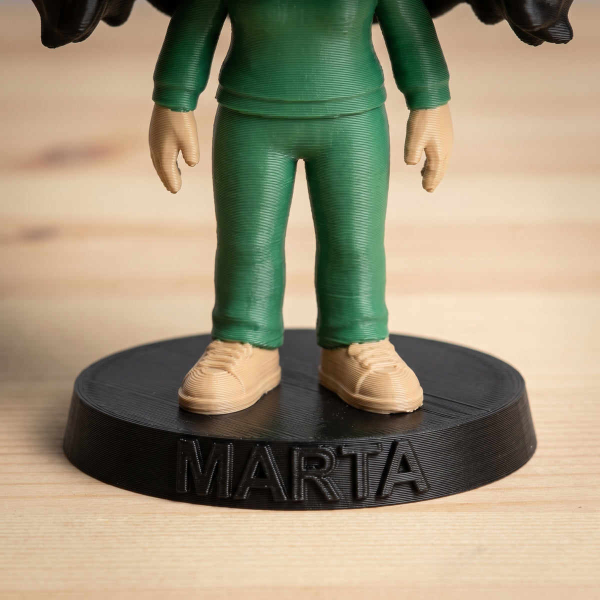 Detalle de la peana con el nombre en relieve y las capas de impresión 3D