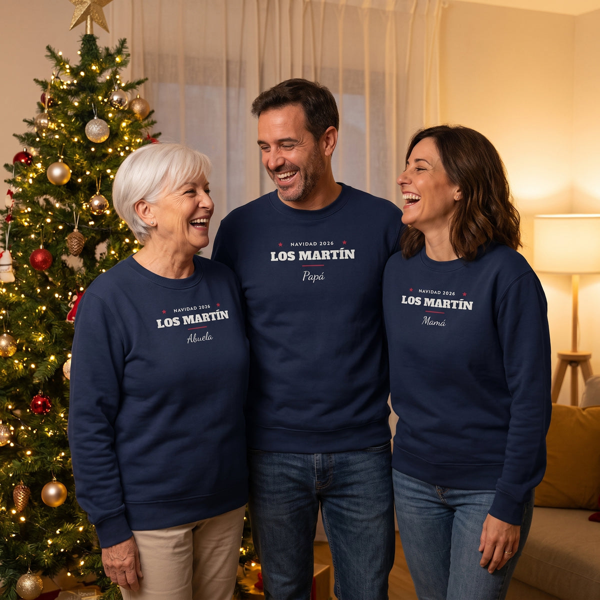 Abuela, padre y madre junto al árbol de Navidad con sus sudaderas azul marino a juego «LOS MARTÍN · NAVIDAD 2026»: Abuela, Papá y Mamá