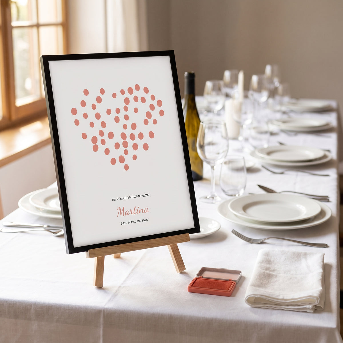 Lámina de huellas de comunión en forma de corazón, en un caballete sobre la mesa de la celebración junto a la almohadilla de tinta