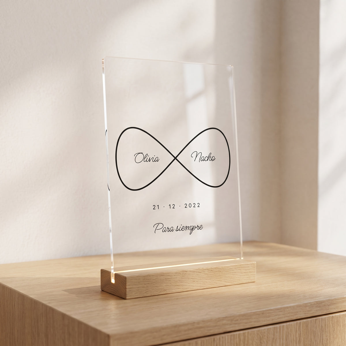 Placa de metacrilato personalizada infinito con nombres sobre un aparador de roble en una habitación luminosa, con su base de madera con luz
