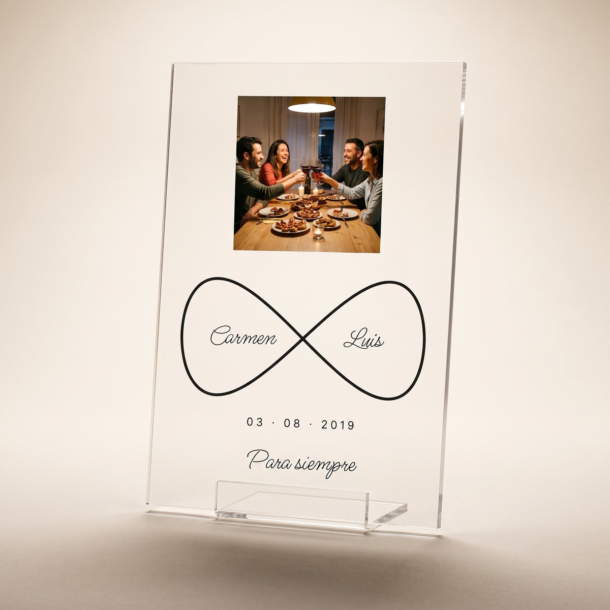 Placa de metacrilato personalizada infinito con nombres en su peana transparente, foto de estudio sobre fondo cálido neutro