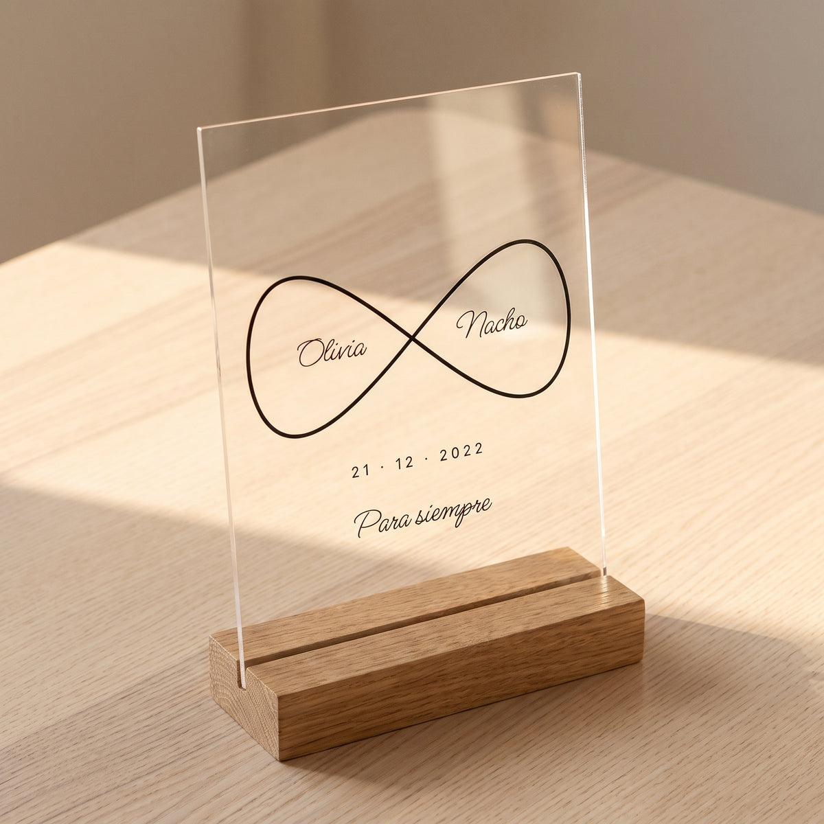 Placa de metacrilato personalizada infinito con nombres encajada en su base de roble, con la luz apagada
