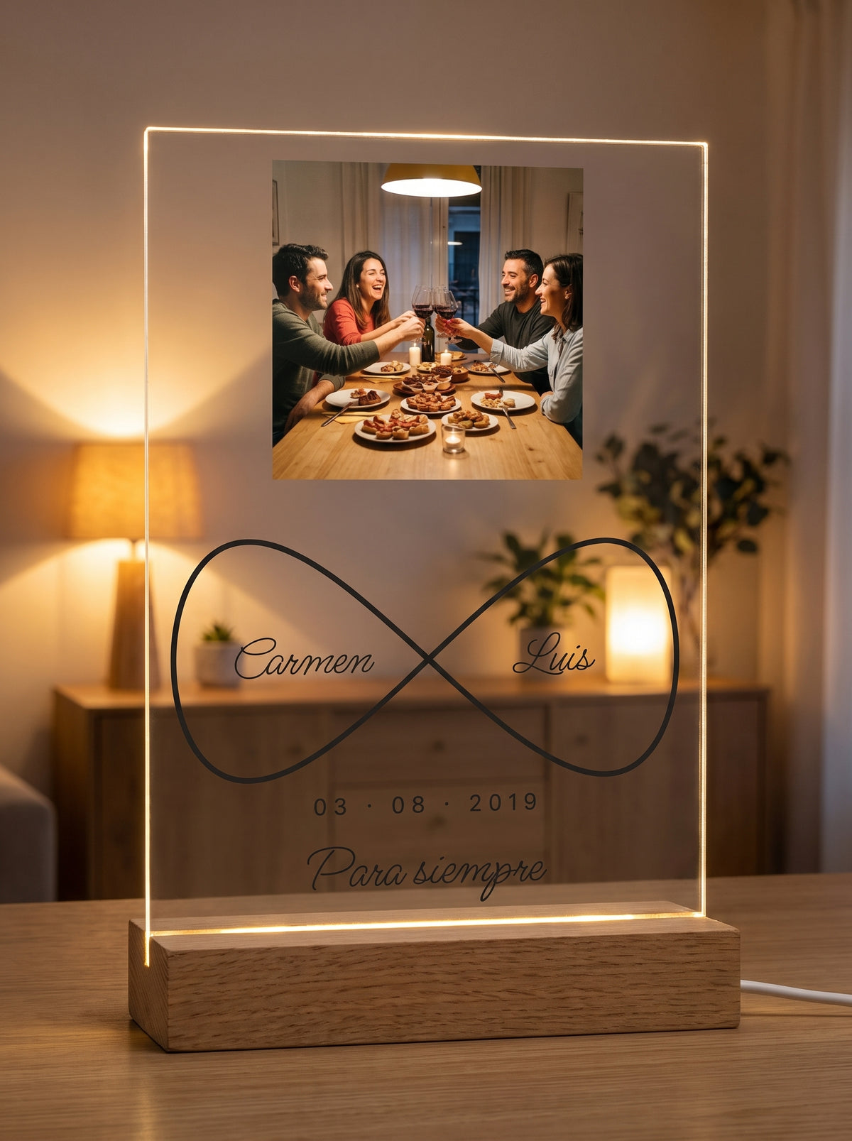 Placa de metacrilato personalizada infinito con nombres encendida sobre su base de roble con luz LED, en un salón al atardecer