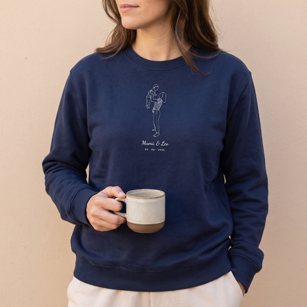Mujer con la sudadera azul marino personalizada con el dibujo lineal de una madre con su bebé y «Mamá & Leo», estampado en el pecho