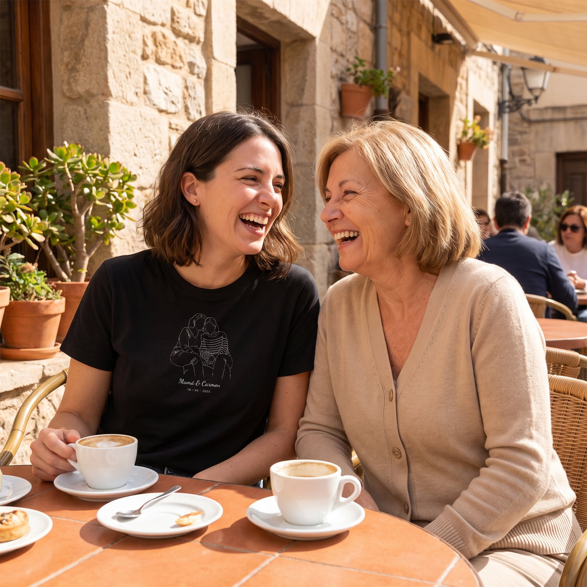 Madre e hija en una terraza; la hija lleva la camiseta negra personalizada con su dibujo lineal y «Mamá & Carmen» estampado en el pecho