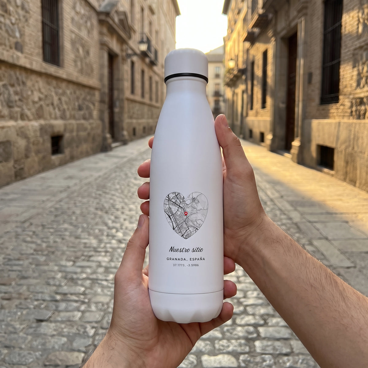 Dos manos sostienen la botella con el mapa de Granada en corazón