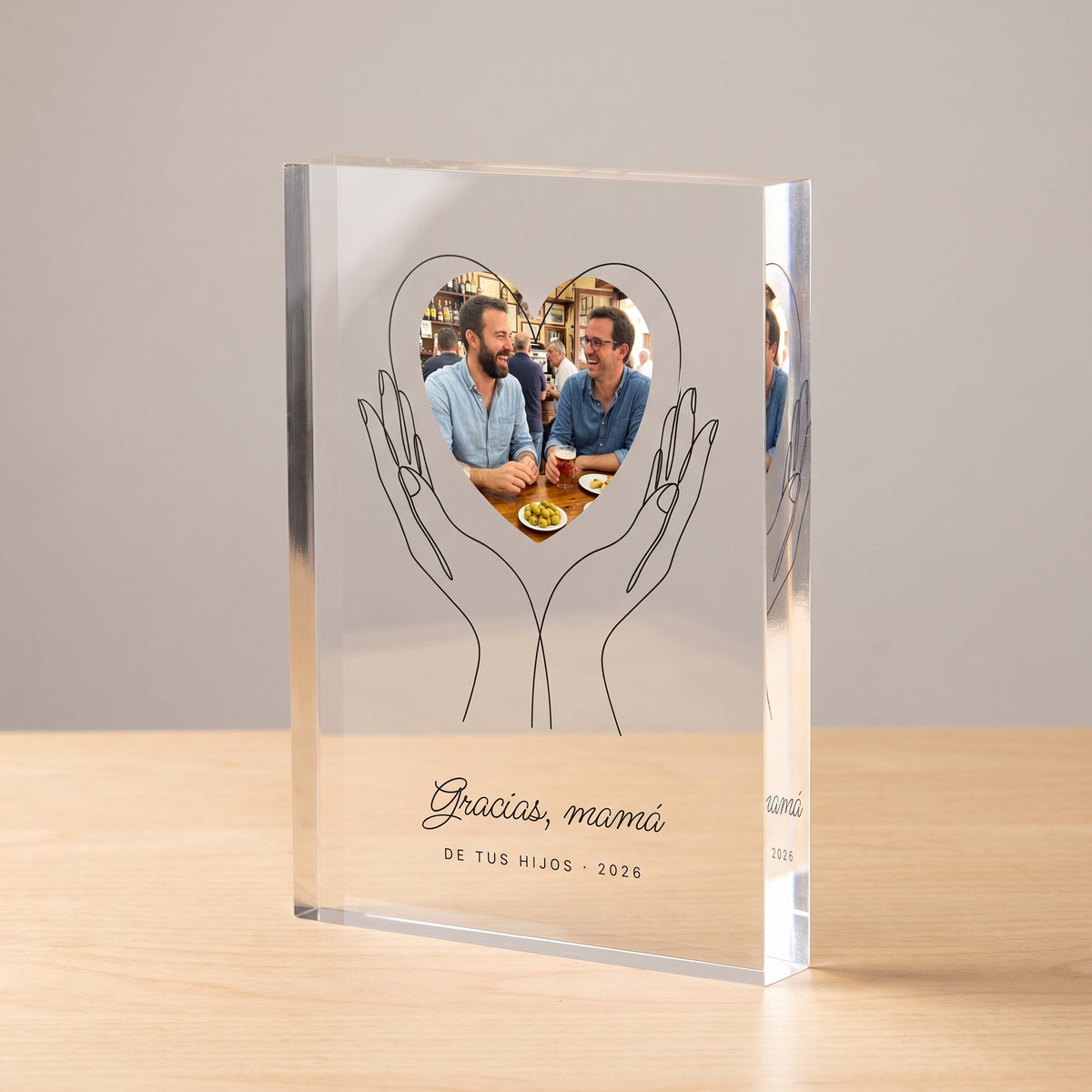 Versión en bloque macizo de 2 cm de la placa de metacrilato personalizada con unas manos que sostienen la foto, girada para ver el canto pulido