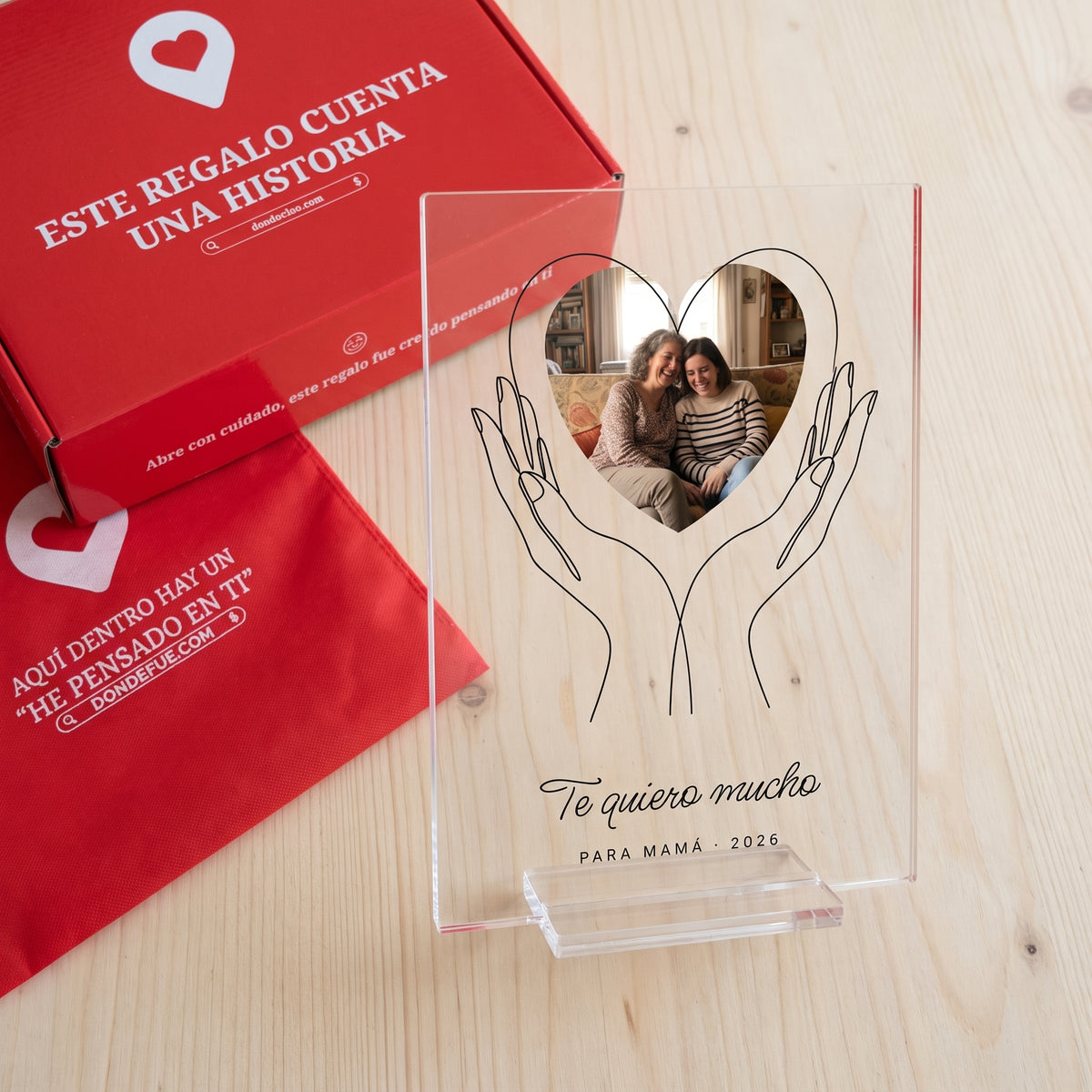 Placa de metacrilato personalizada con unas manos que sostienen la foto junto a la caja y la bolsa de regalo de Donde Fue