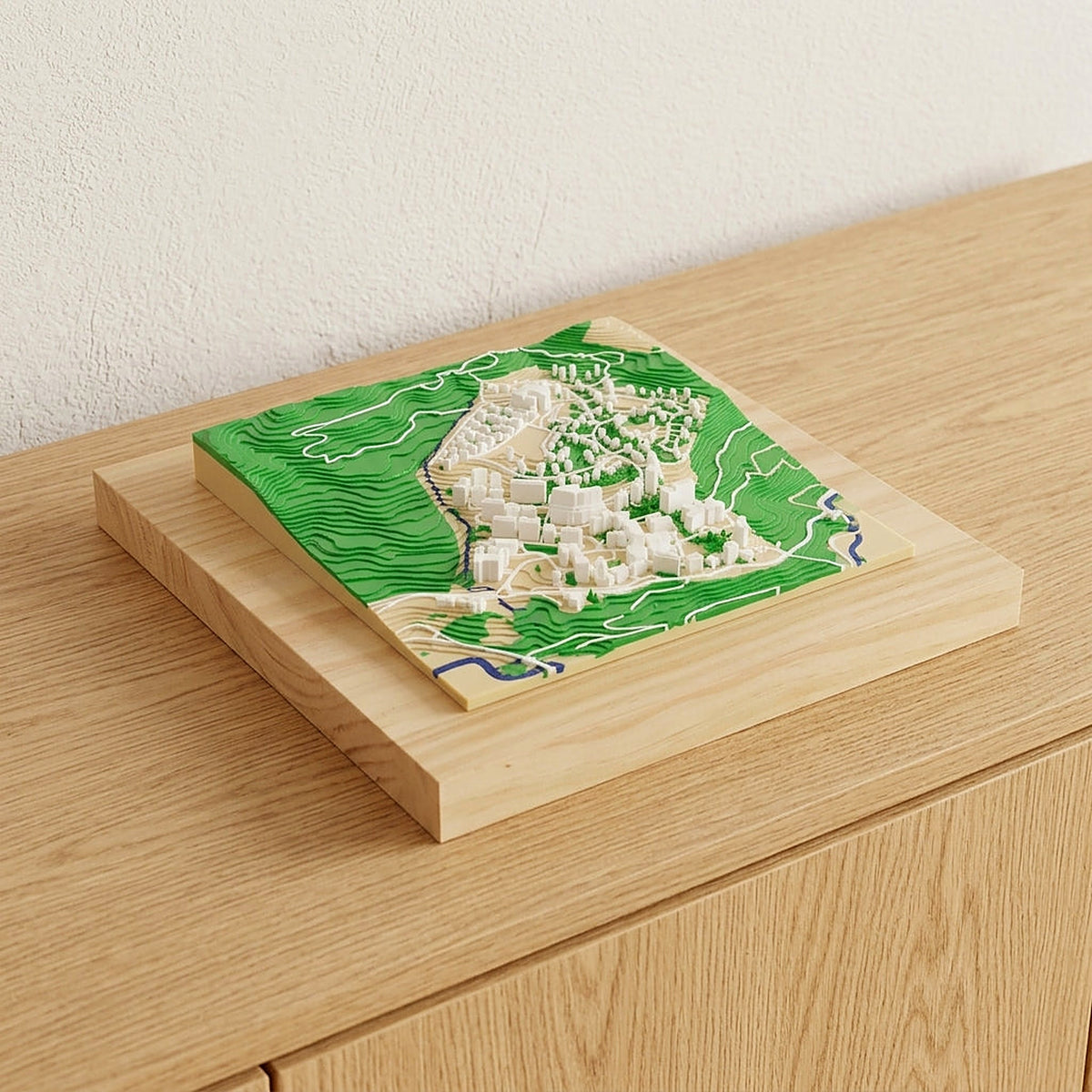 Mapa 3D personalizado de un pueblo con su monte verde y su río, sobre un aparador