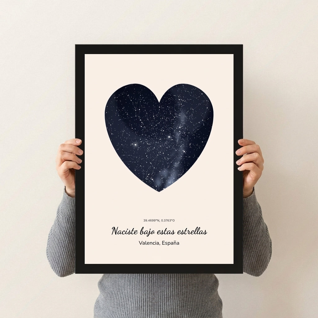 Cuadro mapa estelar de cumpleaños con forma de corazón y marco negro sostenido con las manos