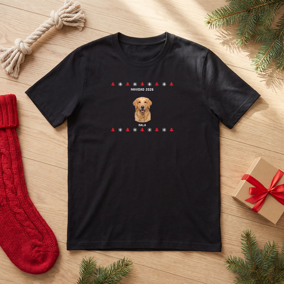 Camiseta negra personalizada con la cara de un golden retriever en estilo jersey de punto navideño, Nala y «Navidad 2026», vista de plano junto a un calcetín de Navidad y un regalo