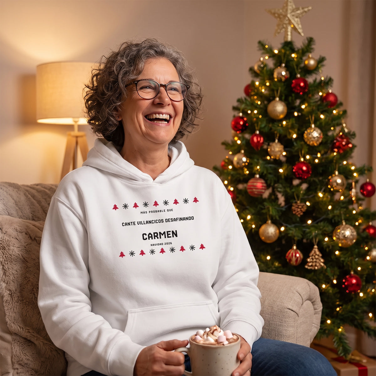 Mujer junto al árbol de Navidad con la sudadera con capucha blanca estilo jersey de punto: «MÁS PROBABLE QUE CANTE VILLANCICOS DESAFINANDO», Carmen
