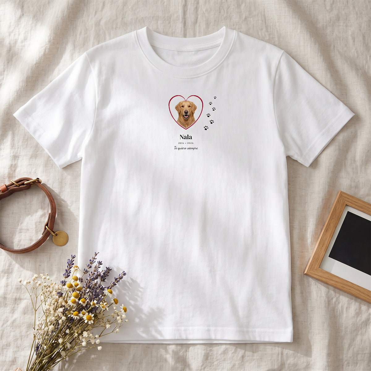 Camiseta blanca personalizada en recuerdo de una golden retriever, Nala, con su foto en un corazón y huellas, junto a su collar, flores secas y un marco