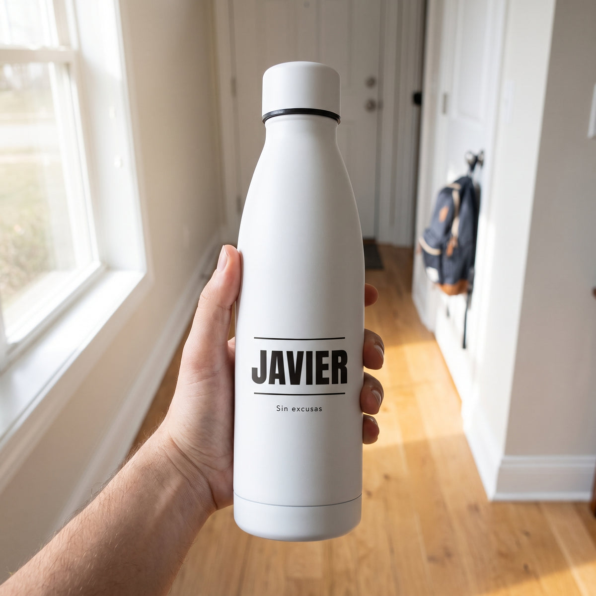 Una mano sostiene la botella con el nombre JAVIER entre filetes