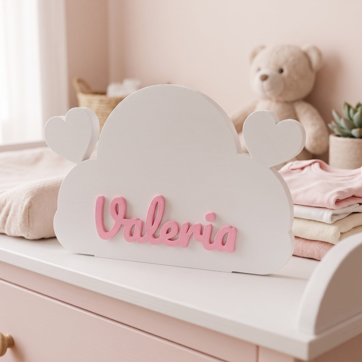 Nube con corazones y el nombre Valeria en rosa sobre el cambiador del bebé