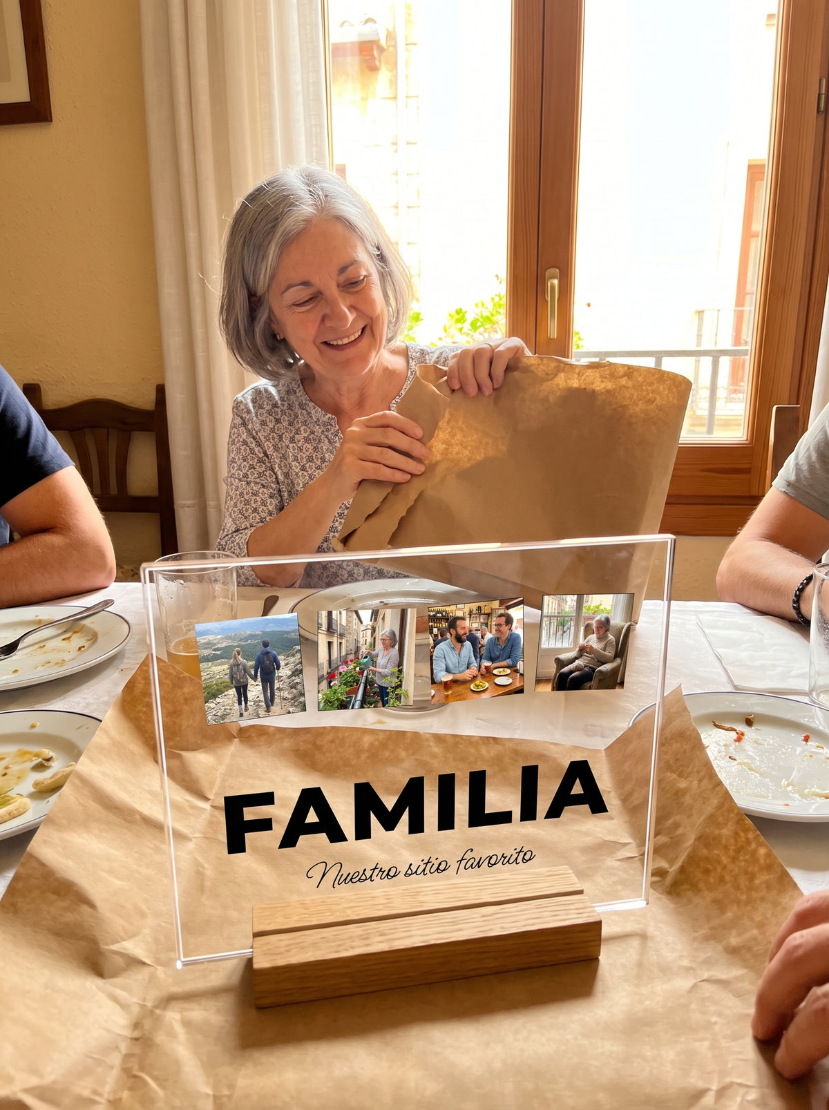 Abriendo el regalo de la placa de metacrilato personalizada con la palabra y cuatro fotos en una comida familiar