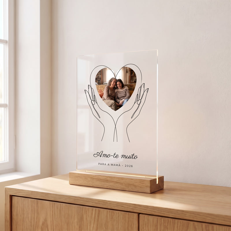 Placa de metacrilato personalizada con unas manos que sostienen la foto sobre un aparador de roble en una habitación luminosa, con su base de madera con luz